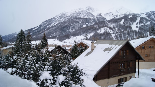 A wooden cabin with a sloped roof, surrounded by snow-covered trees and mountains in the background. - Auberge de Violaine (Monetier-les-Bains)