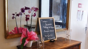 A wooden dresser with a chalkboard sign, a potted orchid, and a mirror. - Auberge de Violaine (Monetier-les-Bains)