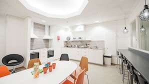 Una cocina moderna con armarios blancos, un comedor con sillas naranjas y una silla negra.