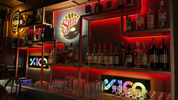 Un espace bar avec des étagères remplies de bouteilles d’alcool et de verres.