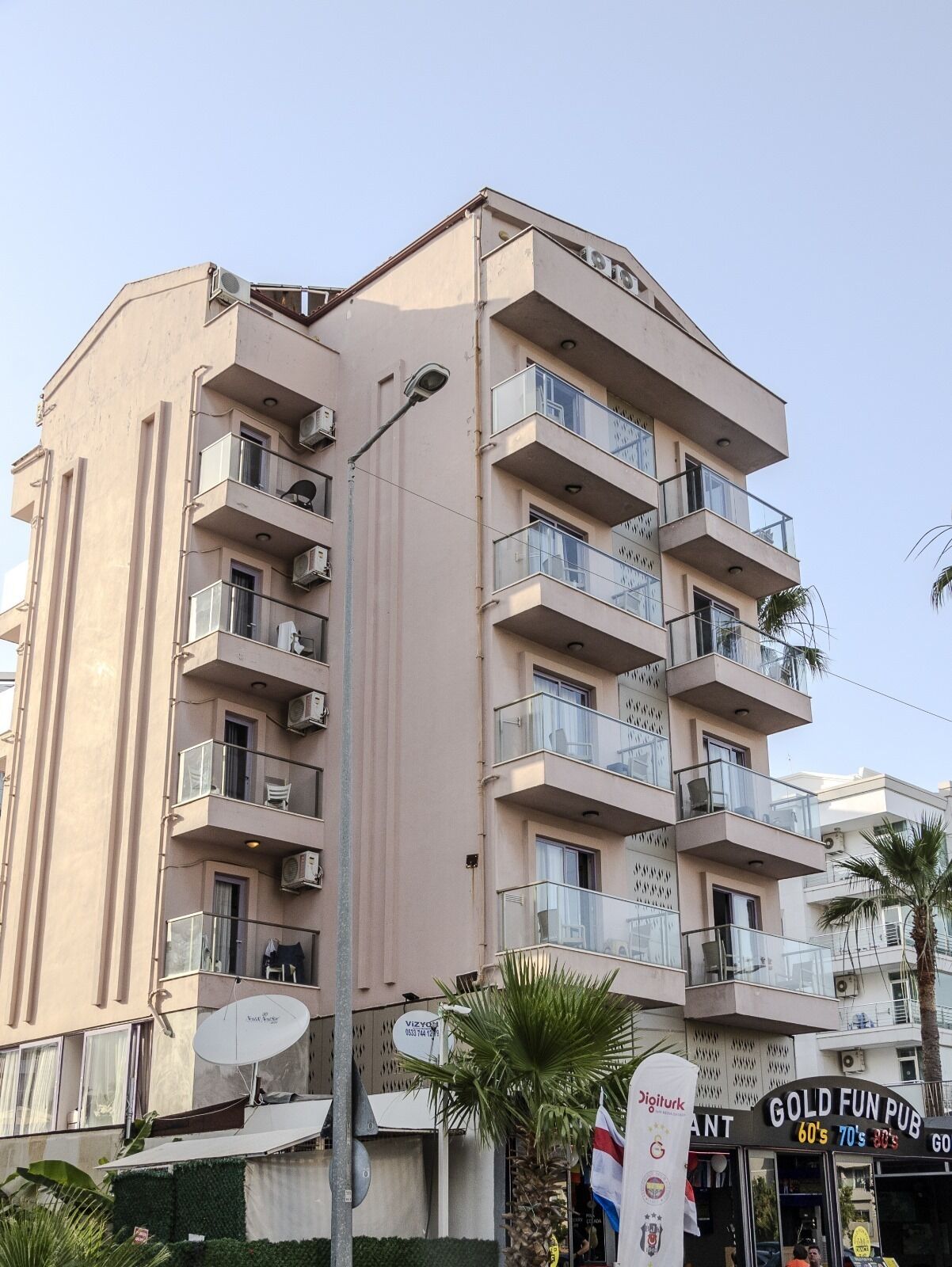 A multi-story building with balconies, a satellite dish, and a sign for 'Gold Fun Pub'.