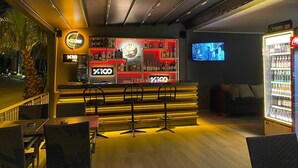 Un espace bar avec un comptoir, des tabourets et un écran de télévision.