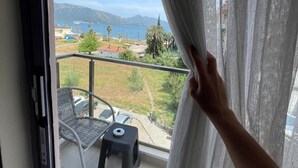 Un balcon offrant une vue sur un paysage côtier, comprenant une étendue d’eau et des montagnes lointaines.