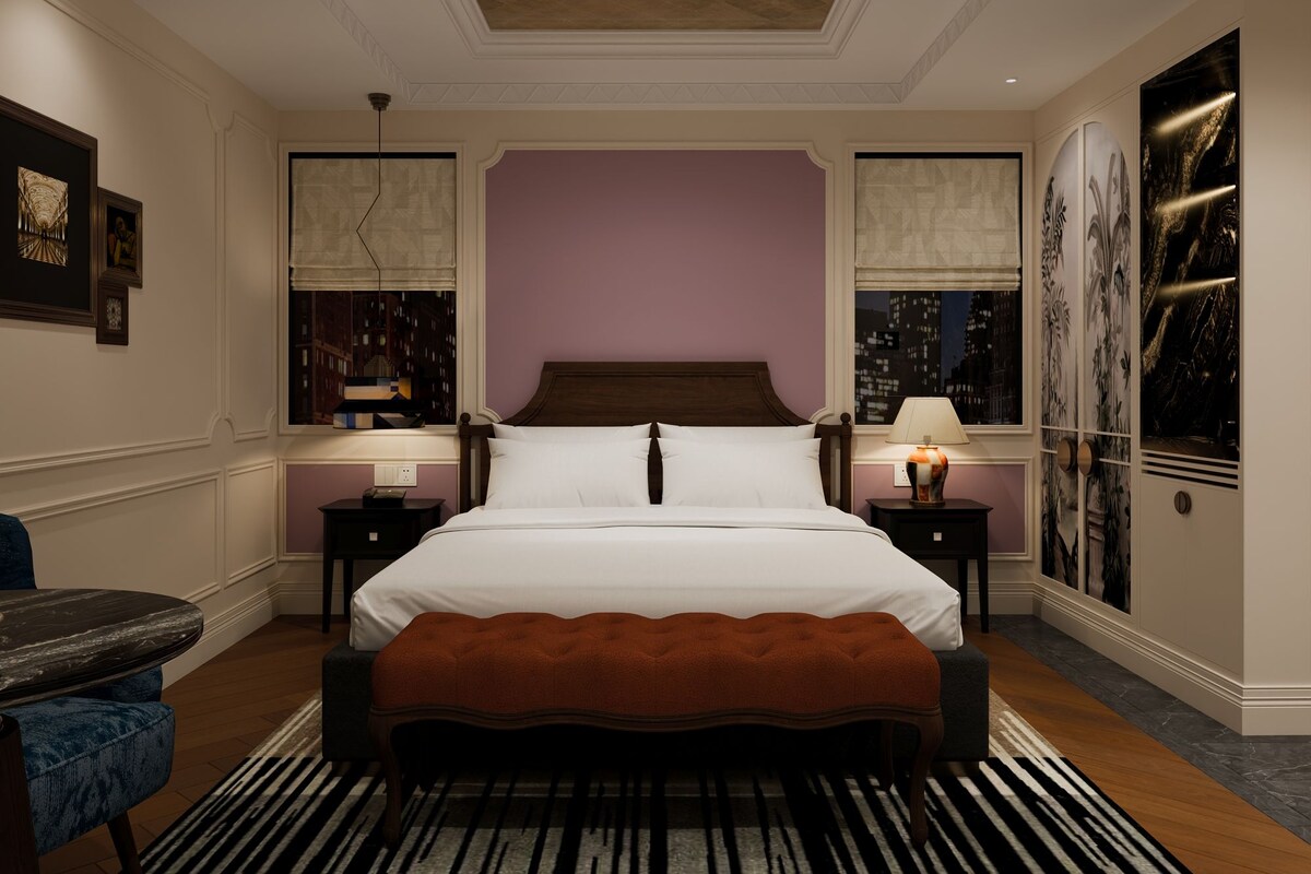 A hotel room with a large bed, two bedside tables, a chair, and a view of the cityscape.