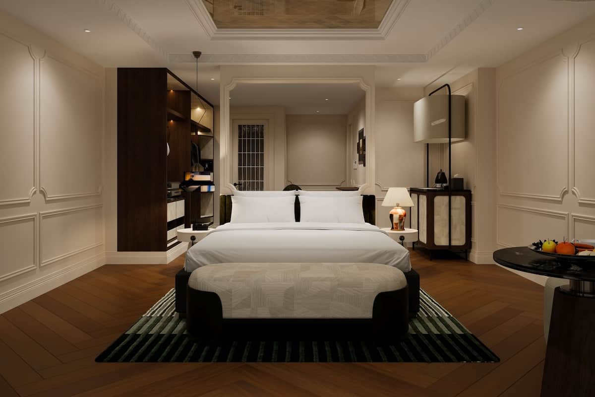 A hotel room with a large bed, a desk, a chair, a mirror, and a view of the hallway.
