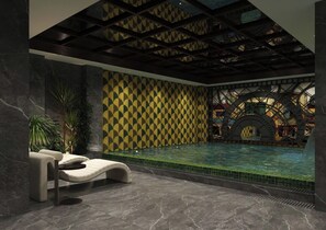 A modern indoor pool area with a geometric patterned wall, a lounge chair, and a large arched structure in the background. - O'Gallery Signature Hotel & Spa (Hanoi)