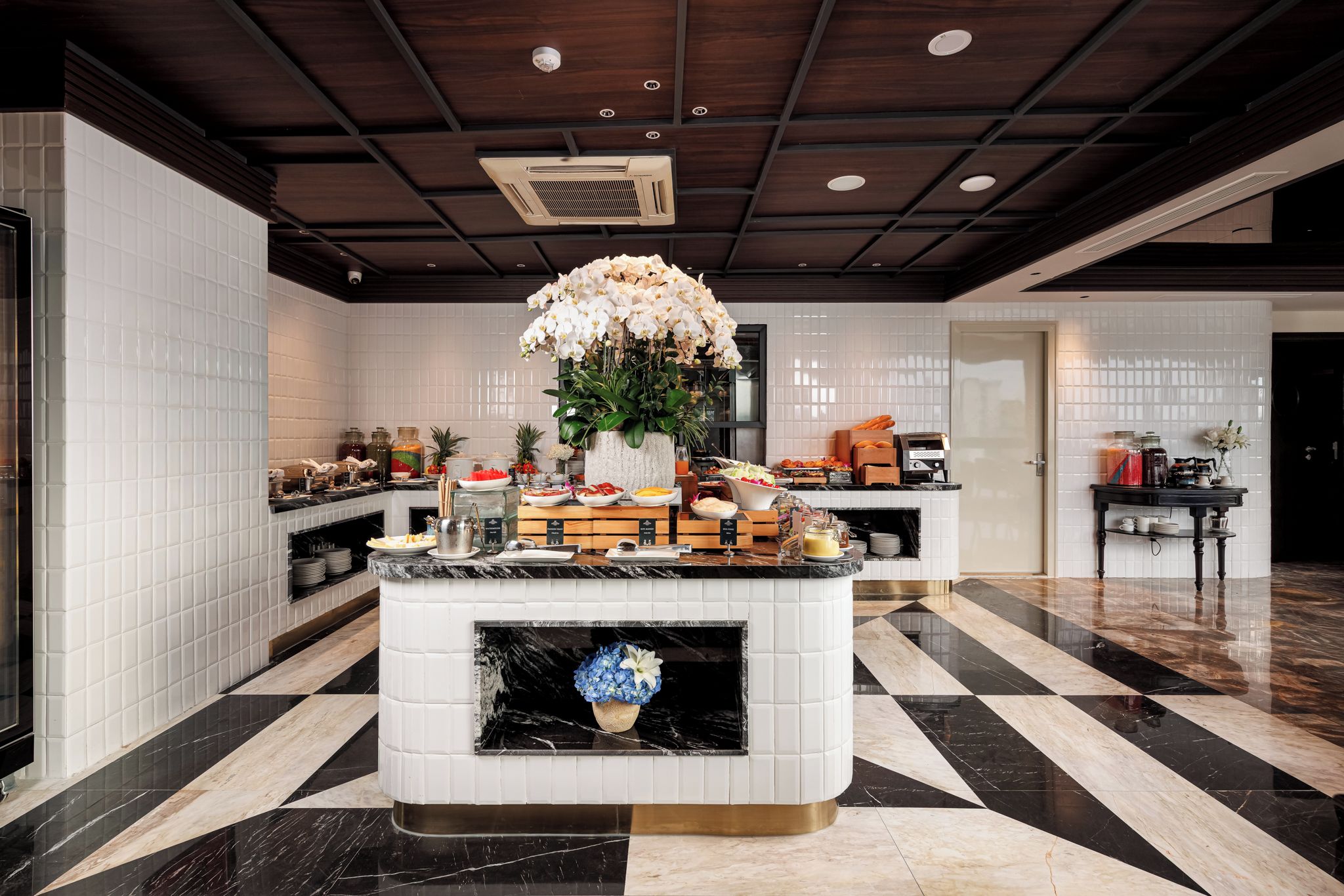 A hotel lobby with a marble floor, a central reception desk, and a fireplace.