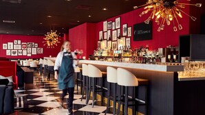 Eine Bar mit Schachbrettboden, roten Wänden und einem Kronleuchter.