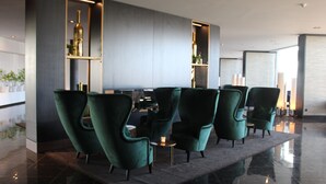 Eine moderne Lobby mit grün gepolsterten Sesseln, einem Marmorboden und einem Tisch in der Mitte mit einer Kerze.