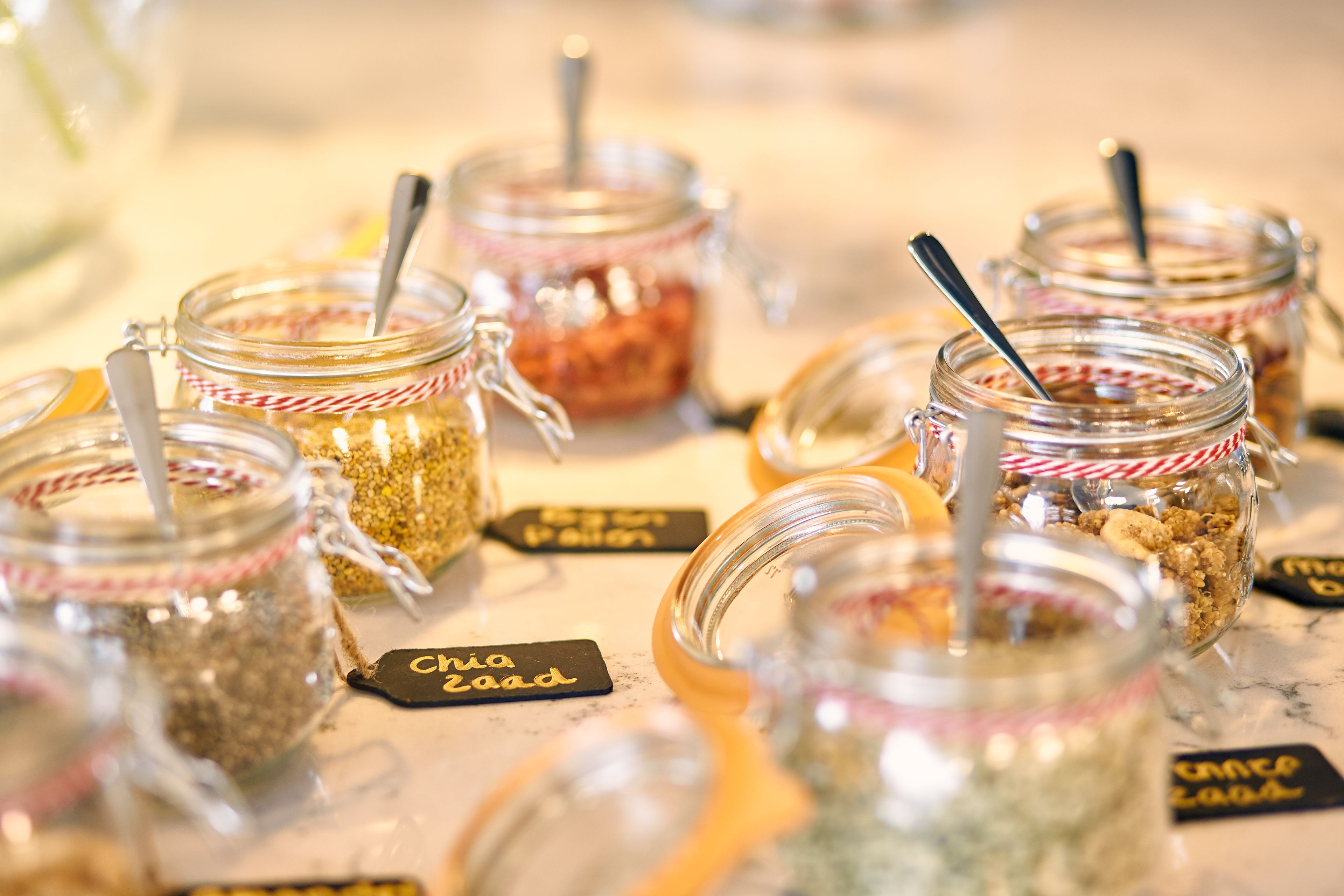 A variety of jars with labels, some containing granola and others with different contents.