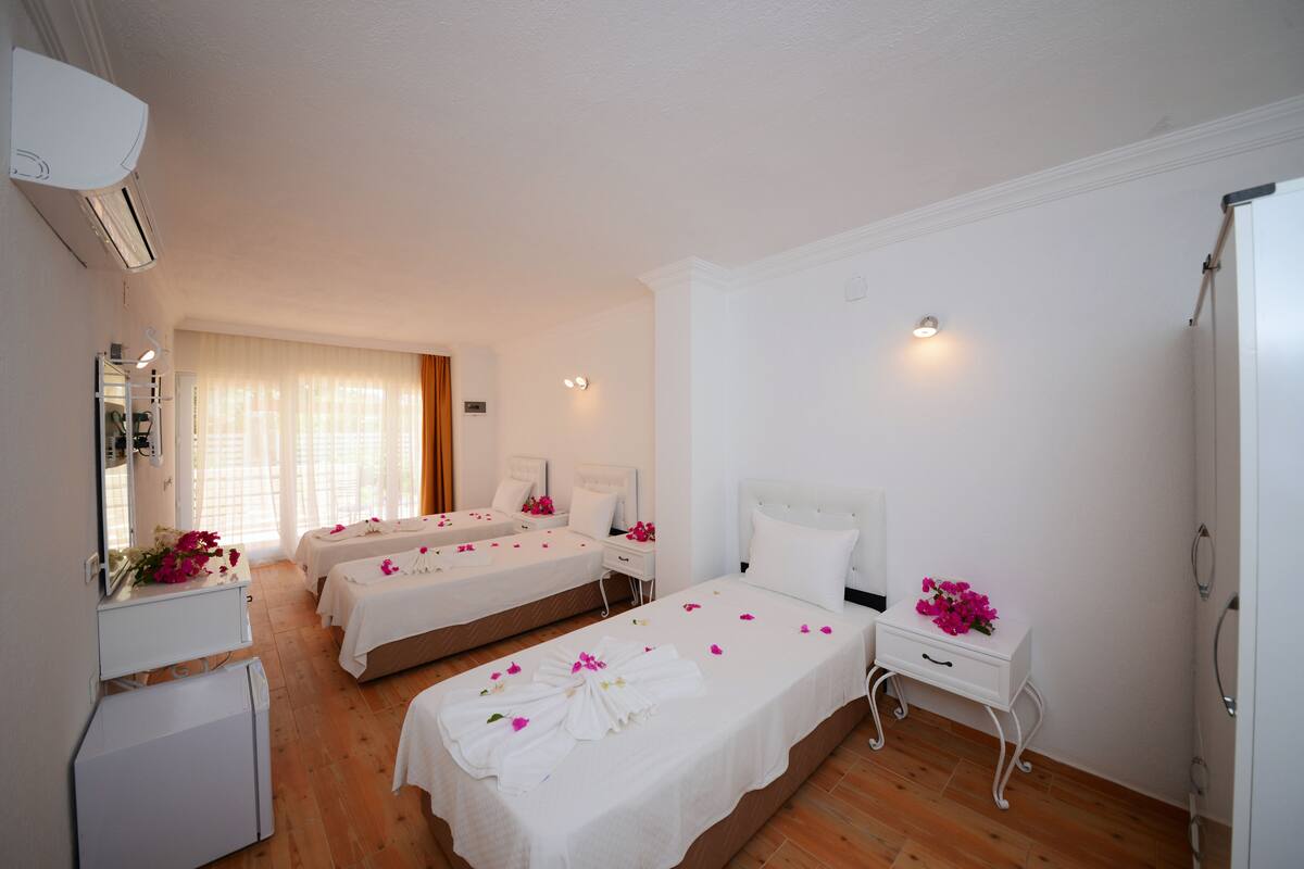 A hotel room with two beds, a small desk, a mirror, and a wardrobe.
