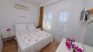 A hotel room with a bed, a nightstand, a mirror, and a window with curtains. - Neruda Hotel (Kas)