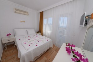 A hotel room with a bed, a nightstand, a mirror, and a window with curtains. - Neruda Hotel (Kas)