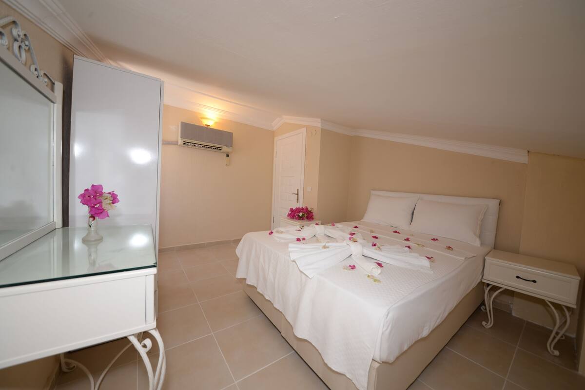 A bedroom with a bed, a bedside table, a nightstand, a dresser, and a mirror.