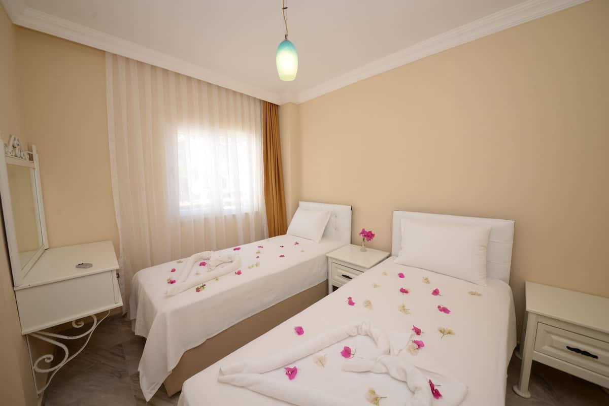 A hotel room with two beds, a vanity with a mirror, and a window with curtains.