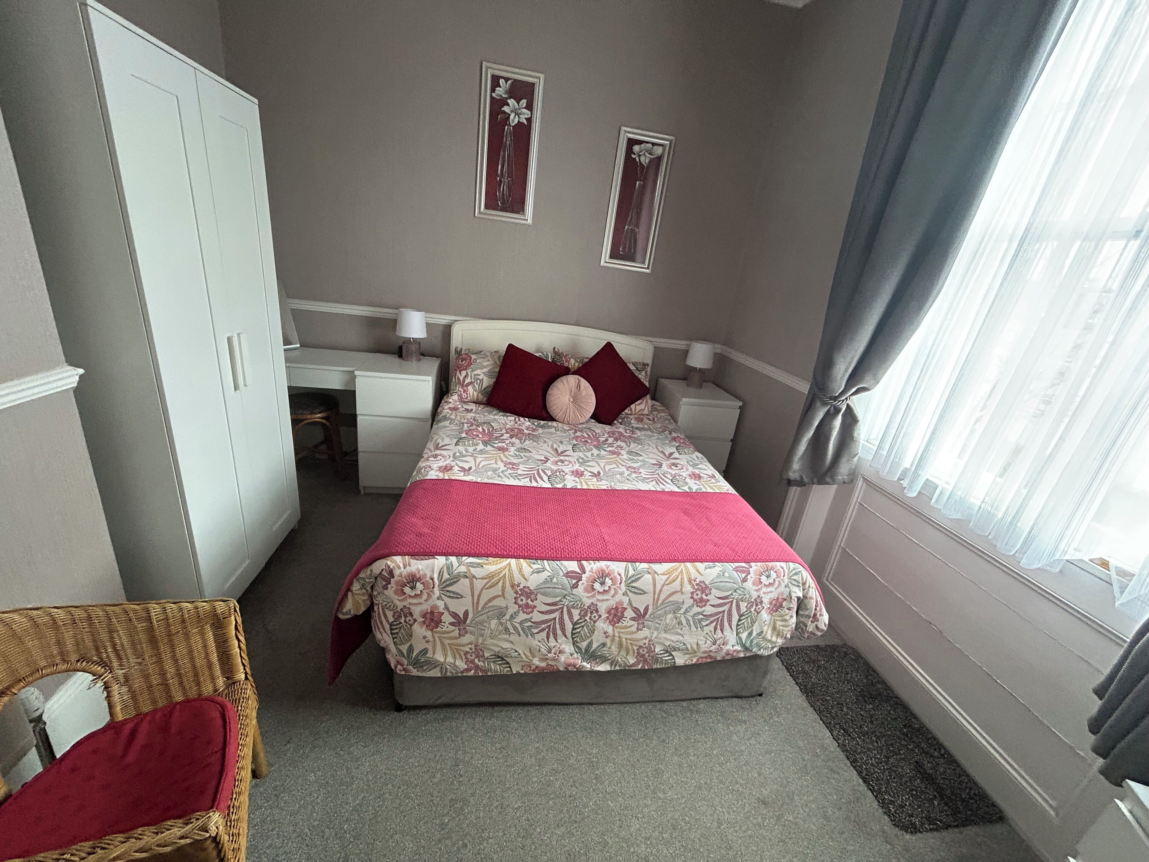A bedroom with a bed, a desk, a chair, and a wardrobe.