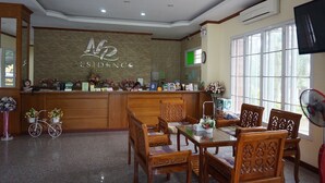 A reception area with a wooden desk, chairs, and a large window. - NP Residence (Nakhon Phanom)