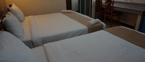 A hotel room with two single beds, a small table, and a chair.