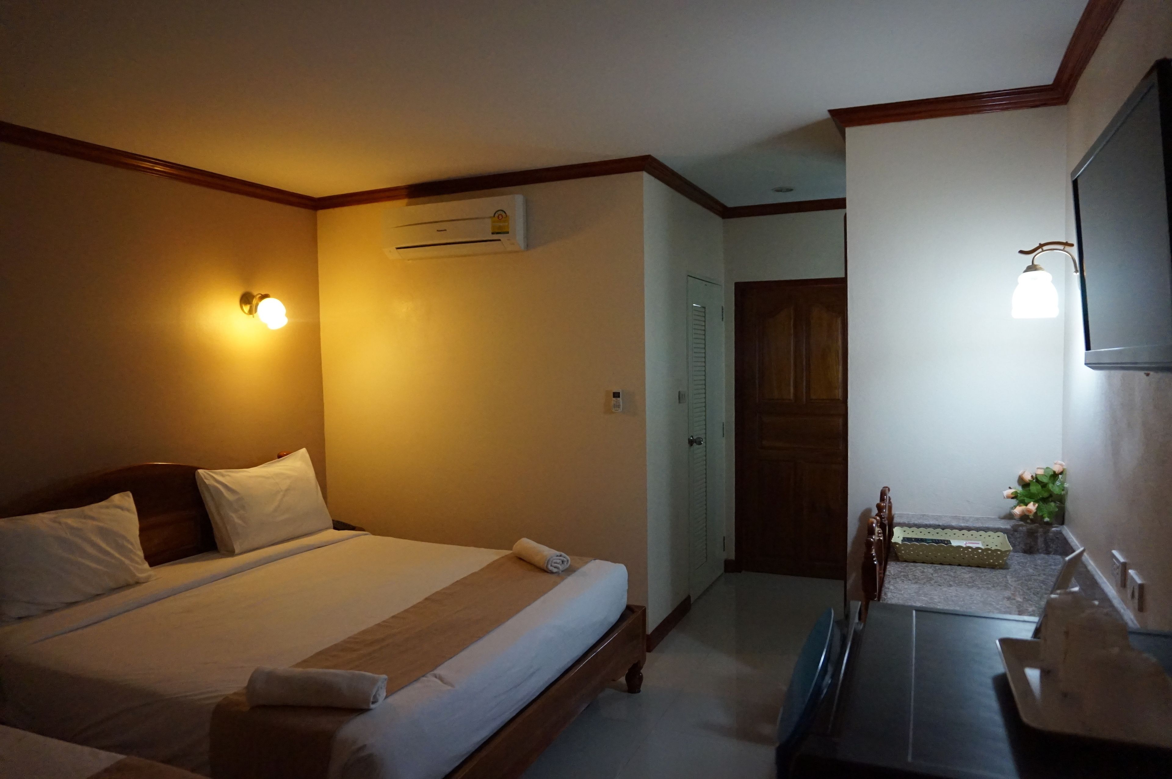 Ein Hotelzimmer mit Bett, Nachttisch, Lampe und Klimaanlage.