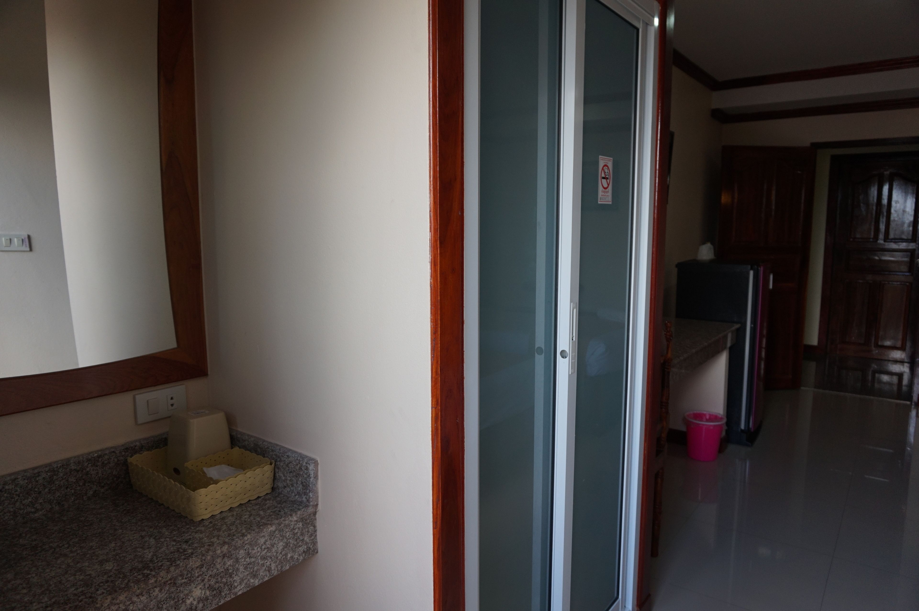 Un couloir avec une porte-fenêtre coulissante, un petit panier accroché au mur et un réfrigérateur à l’arrière-plan.