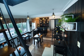 A restaurant interior with multiple tables and chairs, a bar area, and decorative lighting. - Purple Hue Charming Riverside Hotel (Hue)