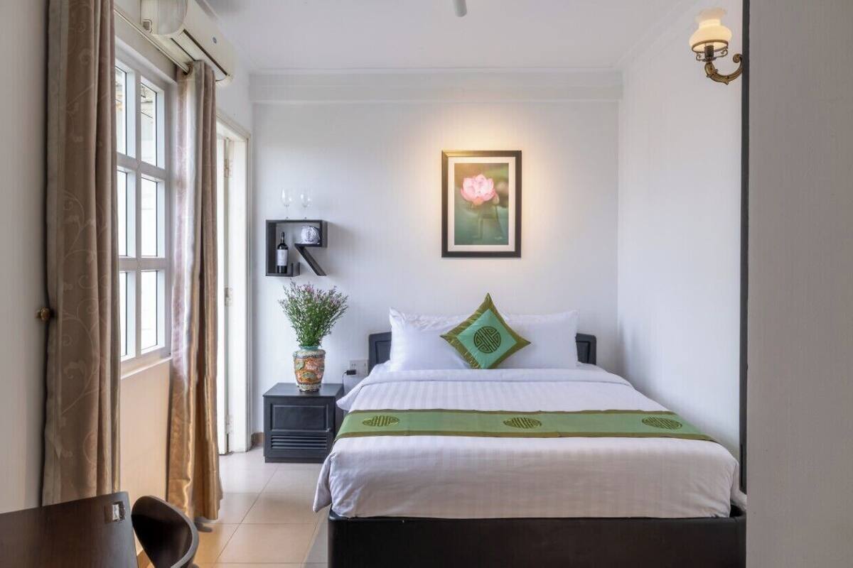 Ein ordentlich eingerichtetes Schlafzimmer mit Bett, Nachttisch und Wandlampe.