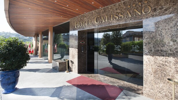 The entrance of Hotel Calissano with a modern design, featuring a curved wooden ceiling and stone facade. - Hotel Calissano (Alba)