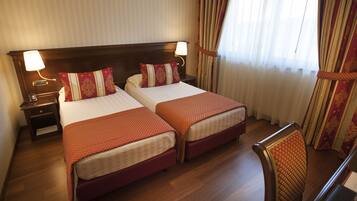 A hotel room with two beds, wooden headboards, and a nightstand with a lamp.
