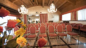 A spacious hall with rows of red upholstered chairs, a chandelier, and a checkered floor pattern.