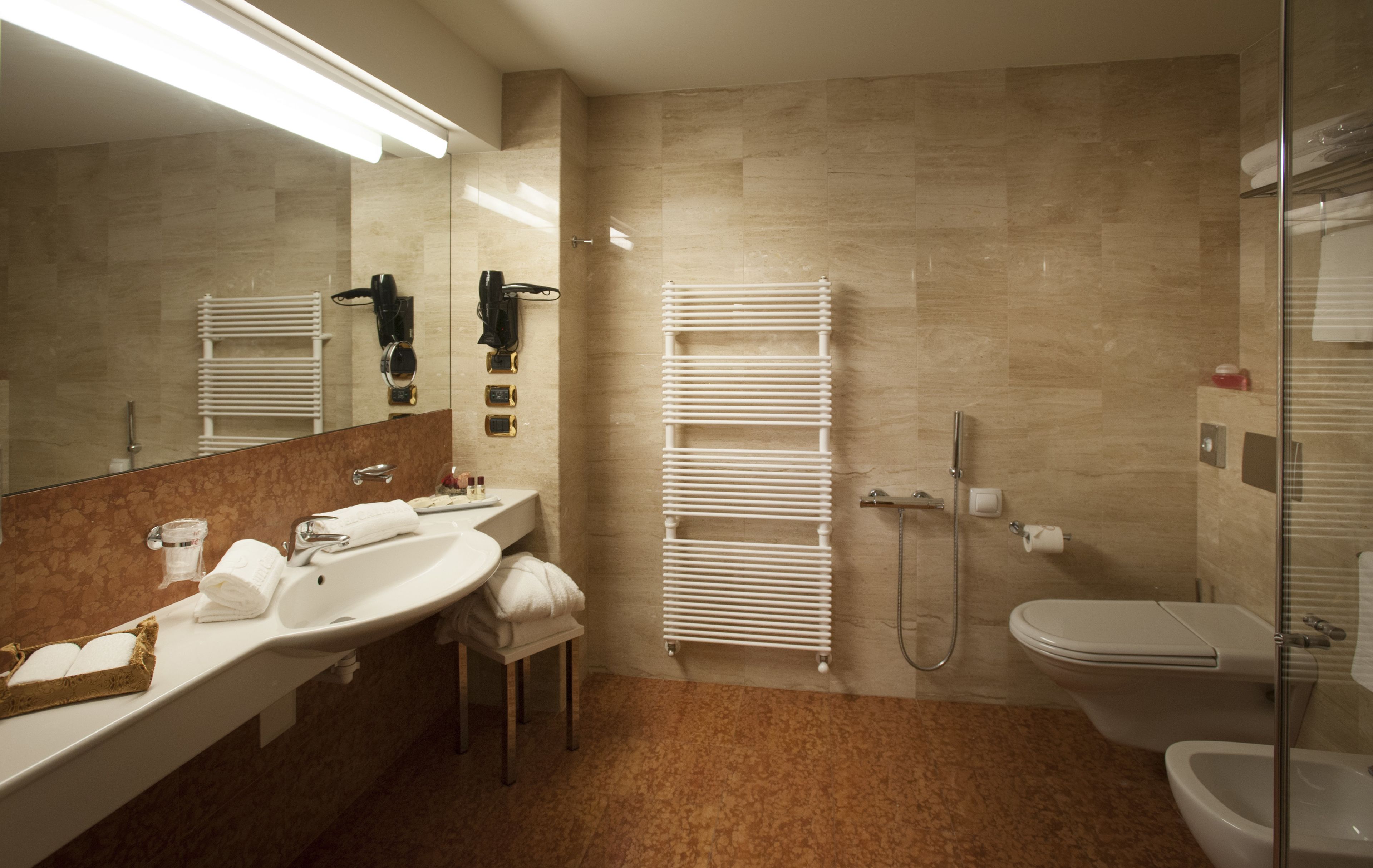 Un baño moderno con dos lavabos, cabina de ducha de vidrio y un inodoro.
