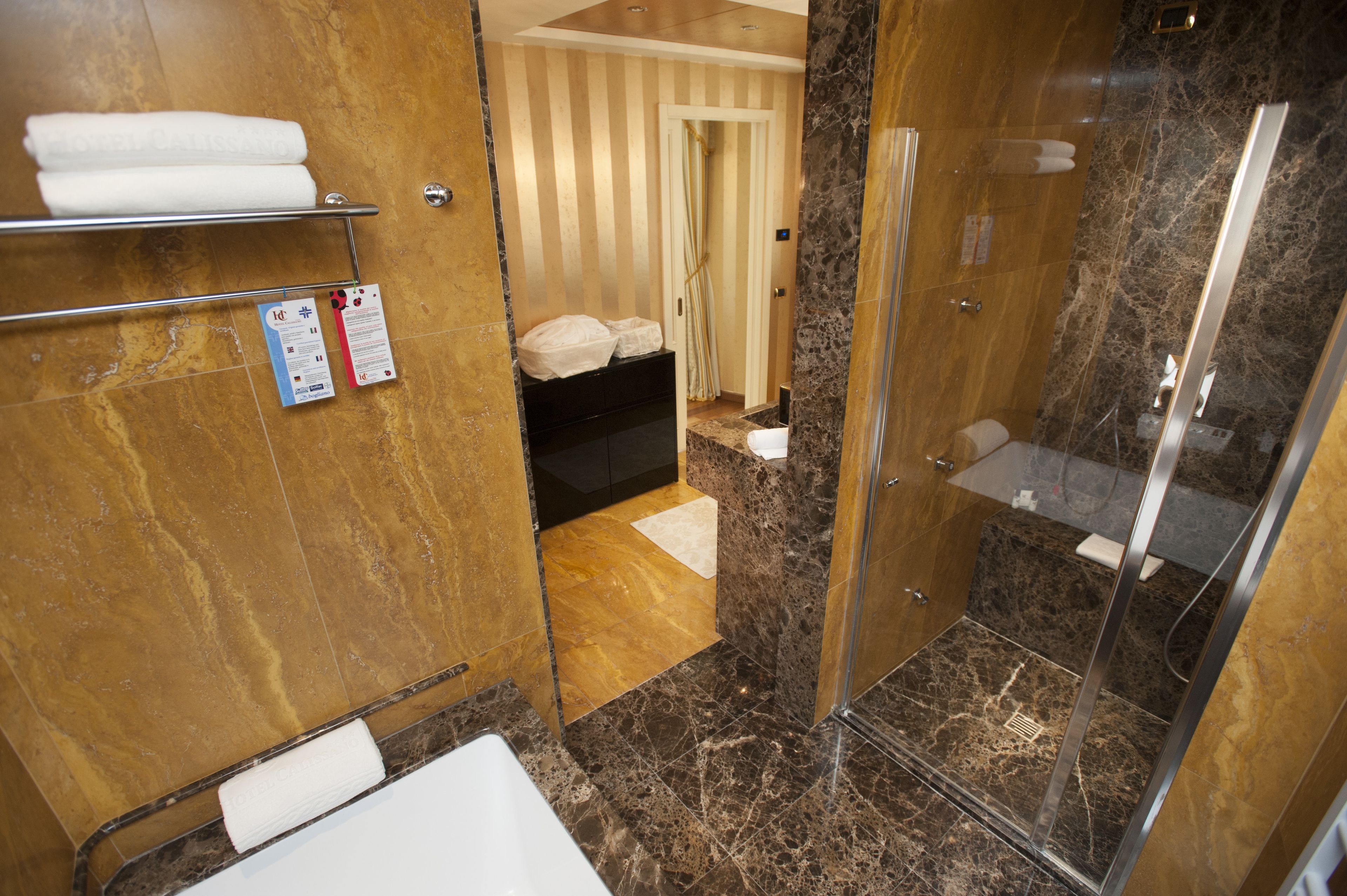 A modern bathroom with a glass-enclosed shower, marble flooring, and a towel rack.