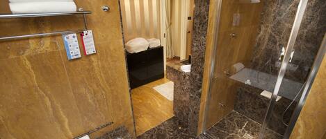 A modern bathroom with a glass-enclosed shower, marble flooring, and a towel rack.