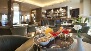 A bar area with a tray of drinks, a bowl of nuts, and a vase with flowers. - Hotel Calissano (Alba)