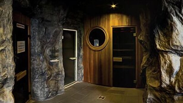 A room with a stone wall, a wooden door, and a circular window. - Shape Sport Hotel (Winsen (Luhe))