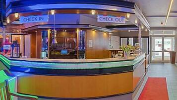 Ein Hotel-Empfangsbereich mit Check-in- und Check-out-Schalter, einer Bank und einem roten Teppich.
