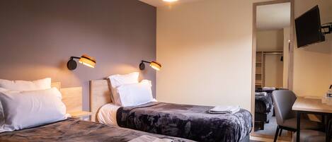 Ett hotellrum med två sängar, ett skrivbord och en TV.