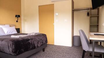 Een hotelkamer met een bed, een bureau, een stoel, een airconditioning en een kledingkast.