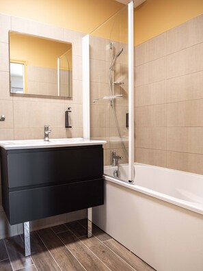 A modern bathroom with a black vanity, a white bathtub, and a glass-enclosed shower. - Le Saint Pierre (Moncoutant-sur-Sèvre)