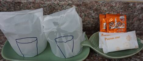 Two paper cups with blue outlines on a green tray, and two packets of soap on another green tray.