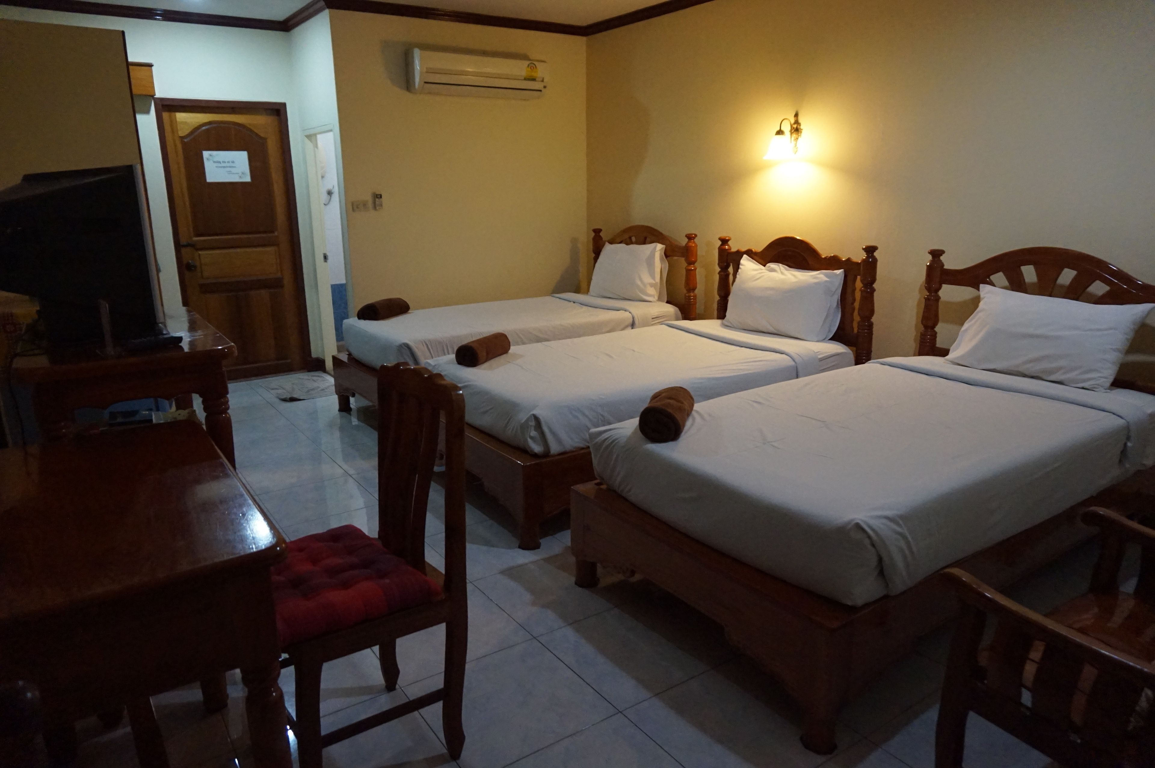 A hotel room with two wooden beds, a desk with a chair, and a television.