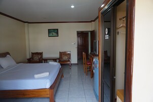 A hotel room with a bed, two chairs, a table, and a washing machine.