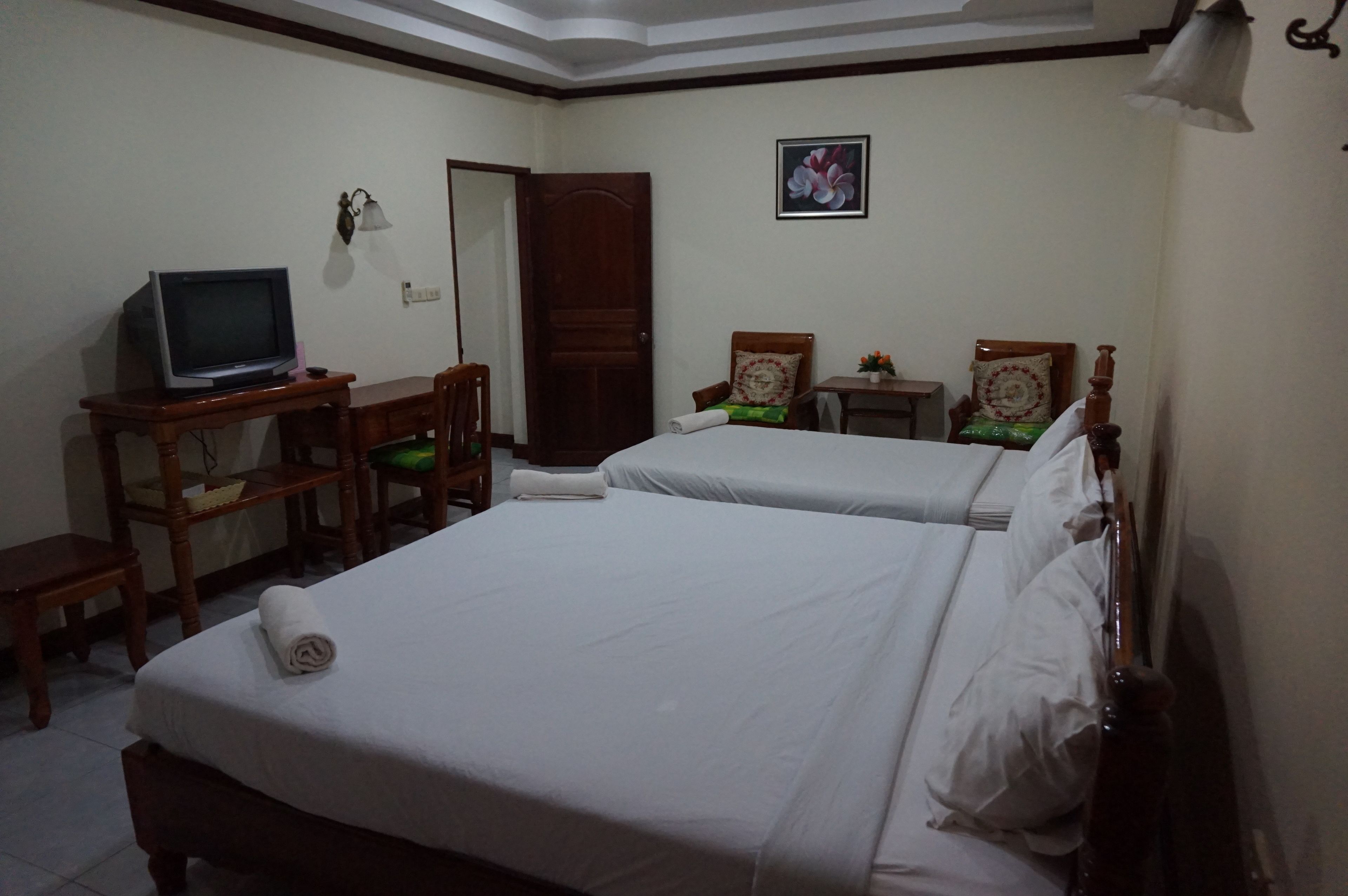 A hotel room with two beds, a desk with a television, and a door.