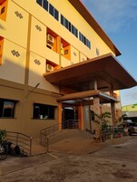 A multi-story building with a flat roof, large windows, and a covered entrance area.