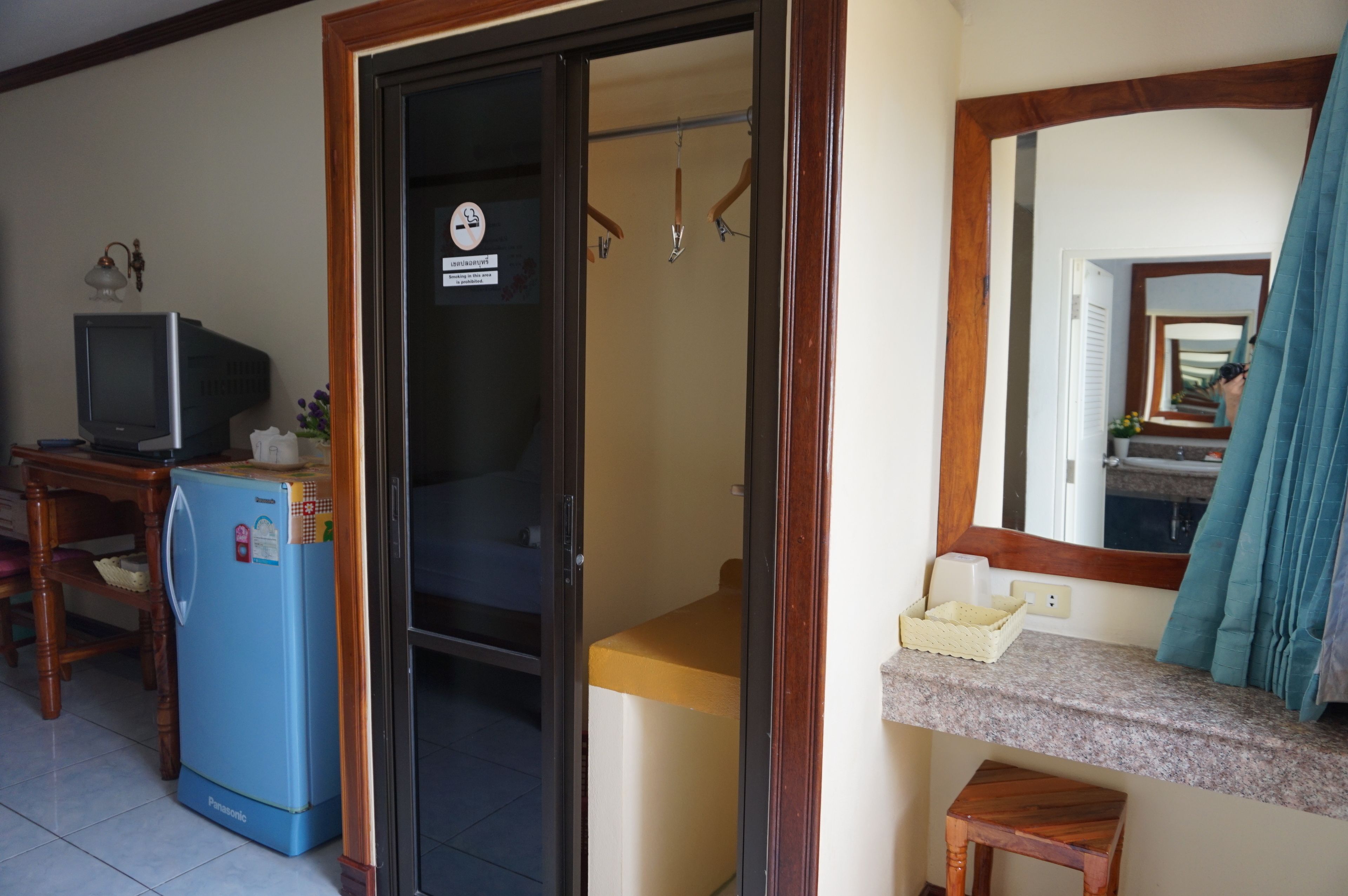 Una habitación compacta con kitchenette, un refrigerador pequeño, televisión y espejo.