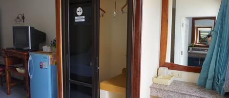 Una habitación compacta con kitchenette, un refrigerador pequeño, televisión y espejo.