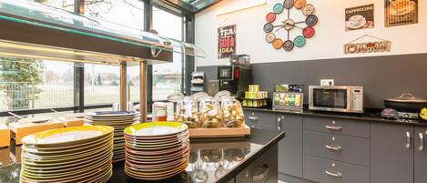 A modern kitchen with a glass enclosure, stainless steel appliances, and a variety of utensils and dishes.