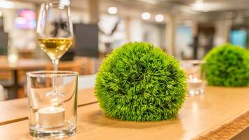 A wooden table with a clear glass candle holder and a green spherical object.