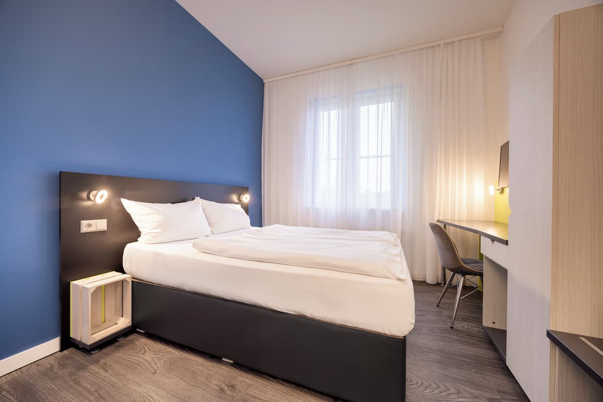Una habitación de hotel moderna con una cama grande, un escritorio y una silla.