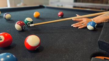 A pool table with various colored balls and a pool cue.