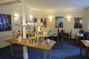 A dining area with a buffet setup, including various food items and a coffee station. - Alpha Hotel-Pension (Hamburg)
